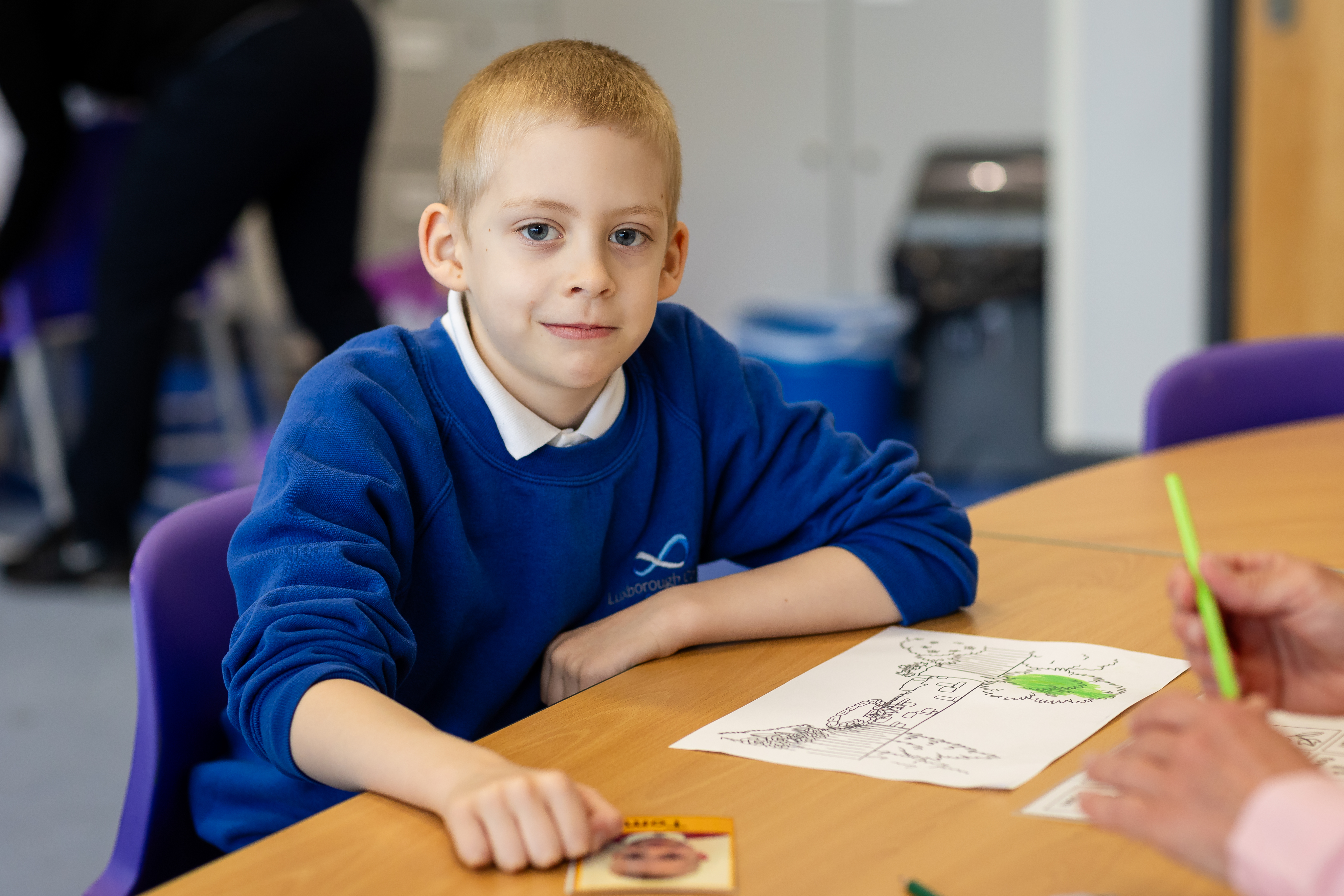 A young boy colouring at Luxborough Court School wearing his school uniform 
