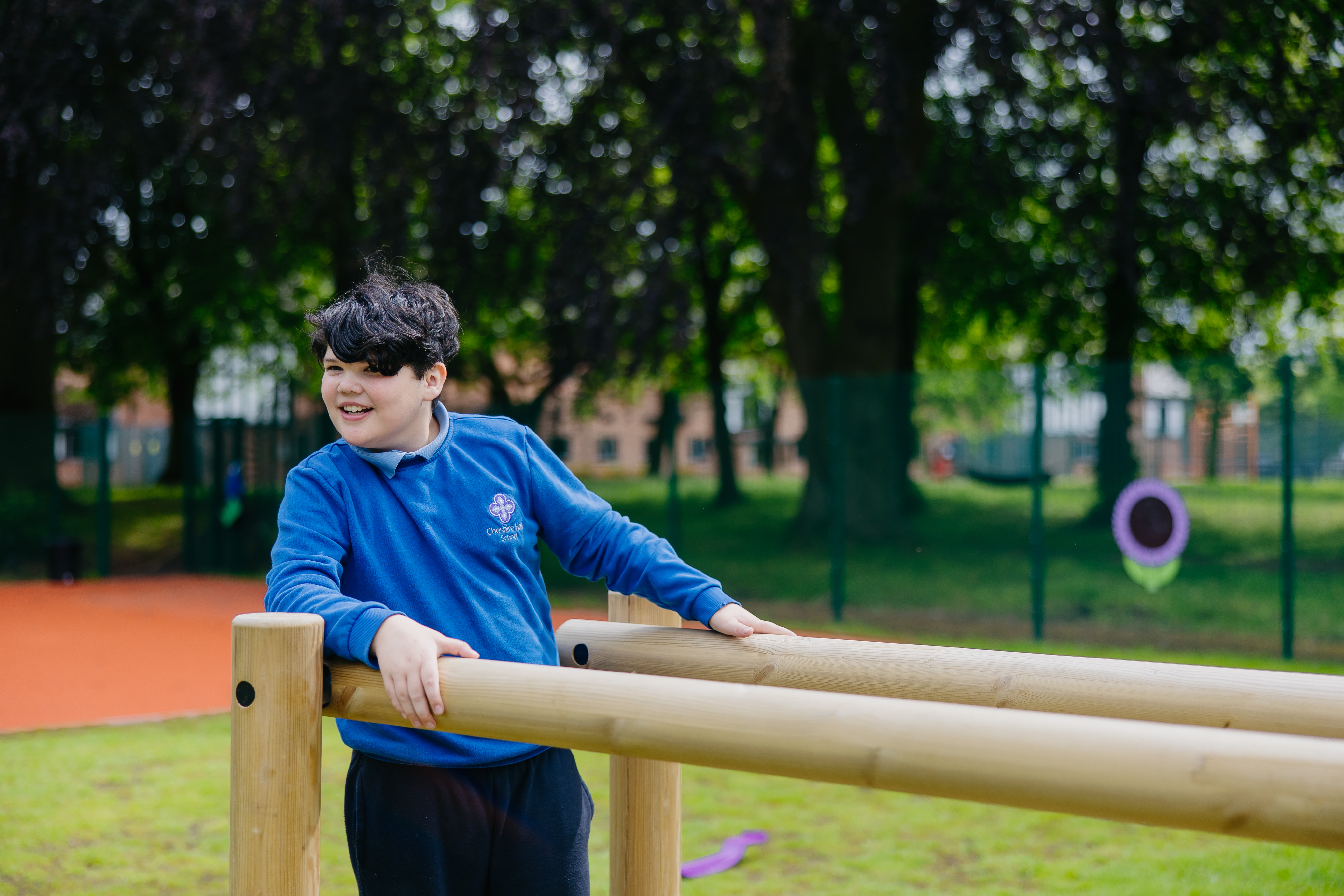 Boy stood on wooden play frame smiling