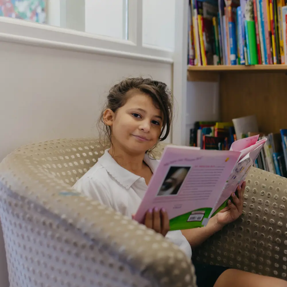 Young girl from Hall Cliffe Primary School reading a book in the library