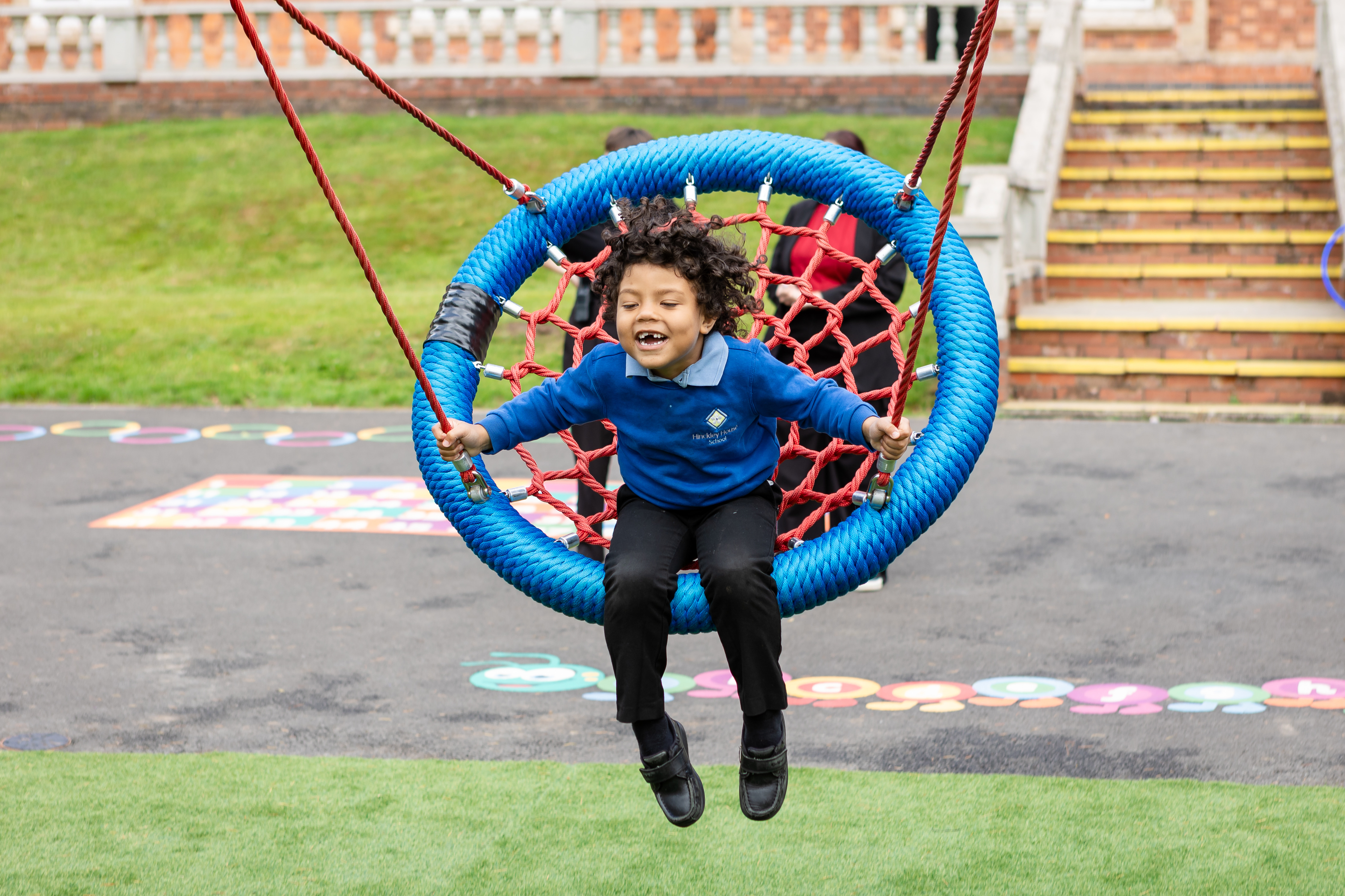 Young boy from Hinckley House School swinging on basket swing and smiling