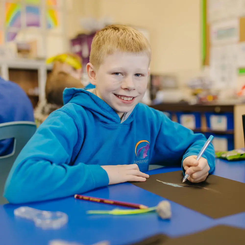 Young boy at Westmorland School smiling working in a classroom
