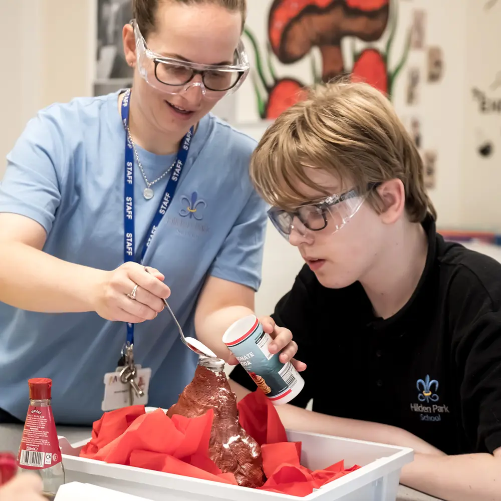 A young boy and a female staff member from Hilden Park School working on a volcano model together