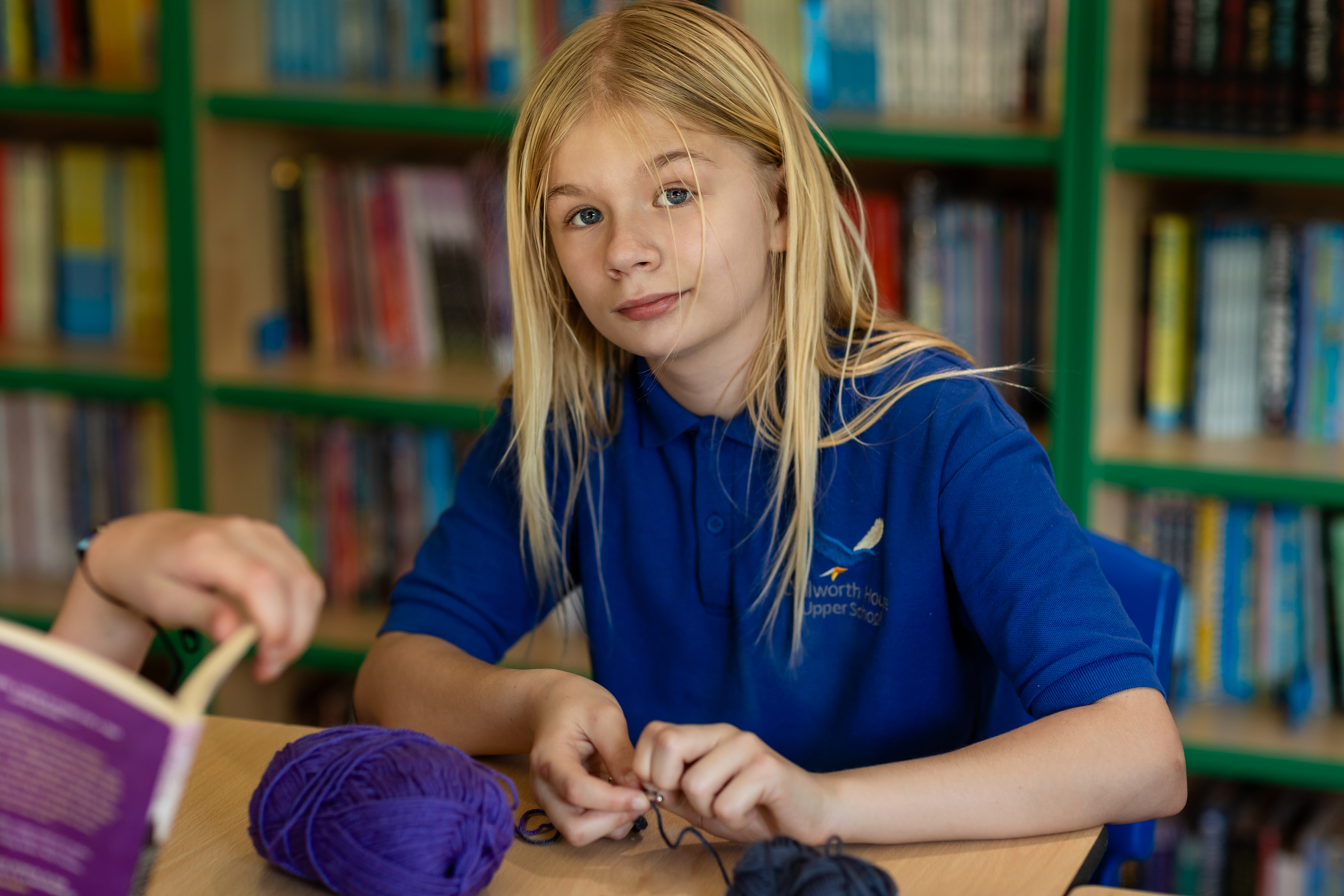 A young girl with long blonde hair with blue eyes at Chilworth House Upper School looking at the camera