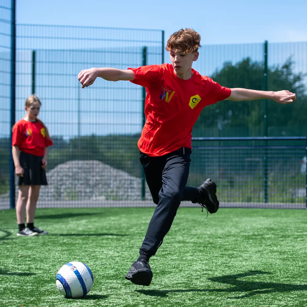A young boy at Lakeside School kicking a football on the Cruyff Court