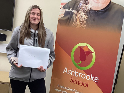 A young girl from Ashbrooke School holding her GCSE results smiling