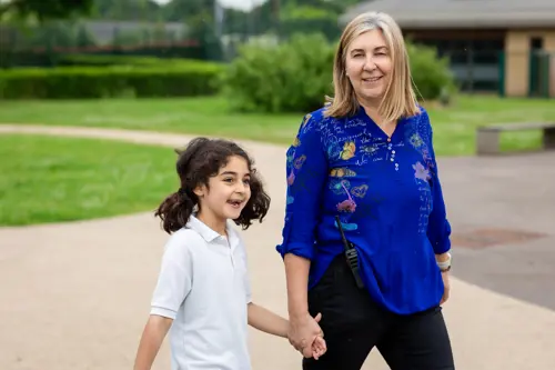 A young girl at Luxborough Court School walking with a teacher outside