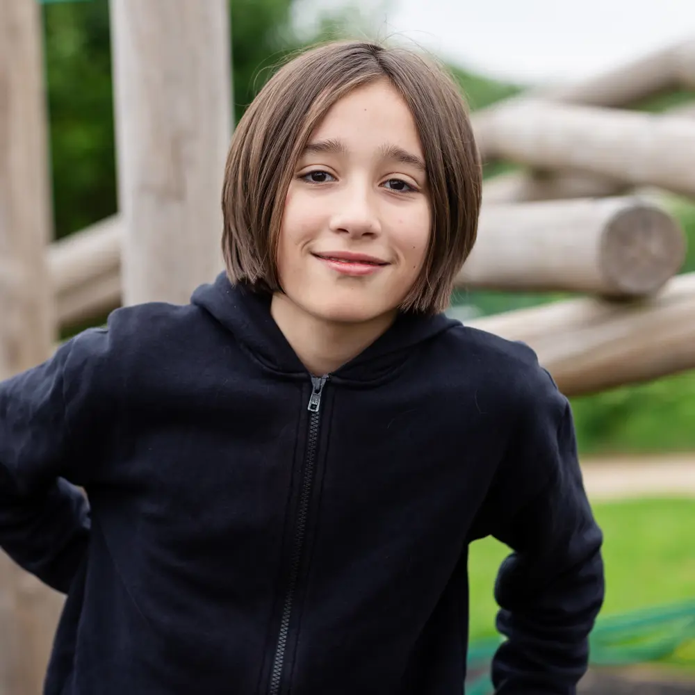 A young boy at Luxborough Court School outside on the play area equipment