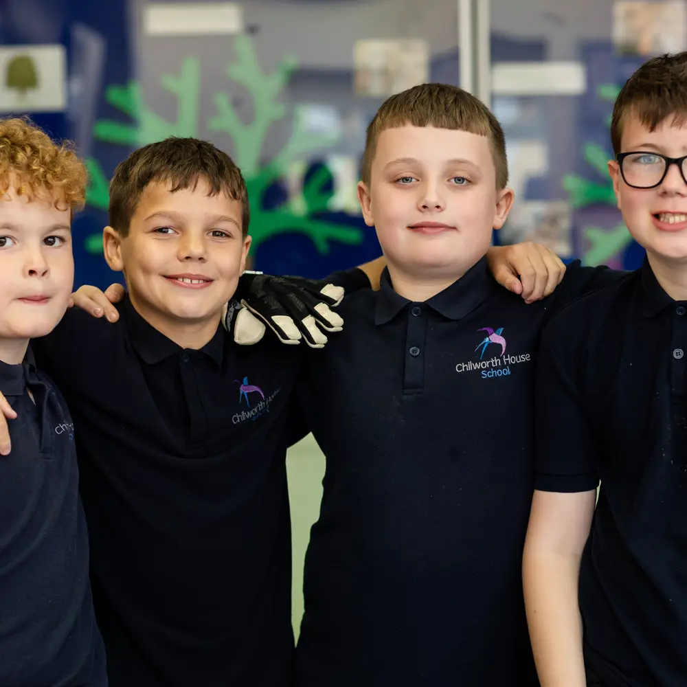 4 boys from Chilworth house School with their arms on each others shoulder smiling into the camera