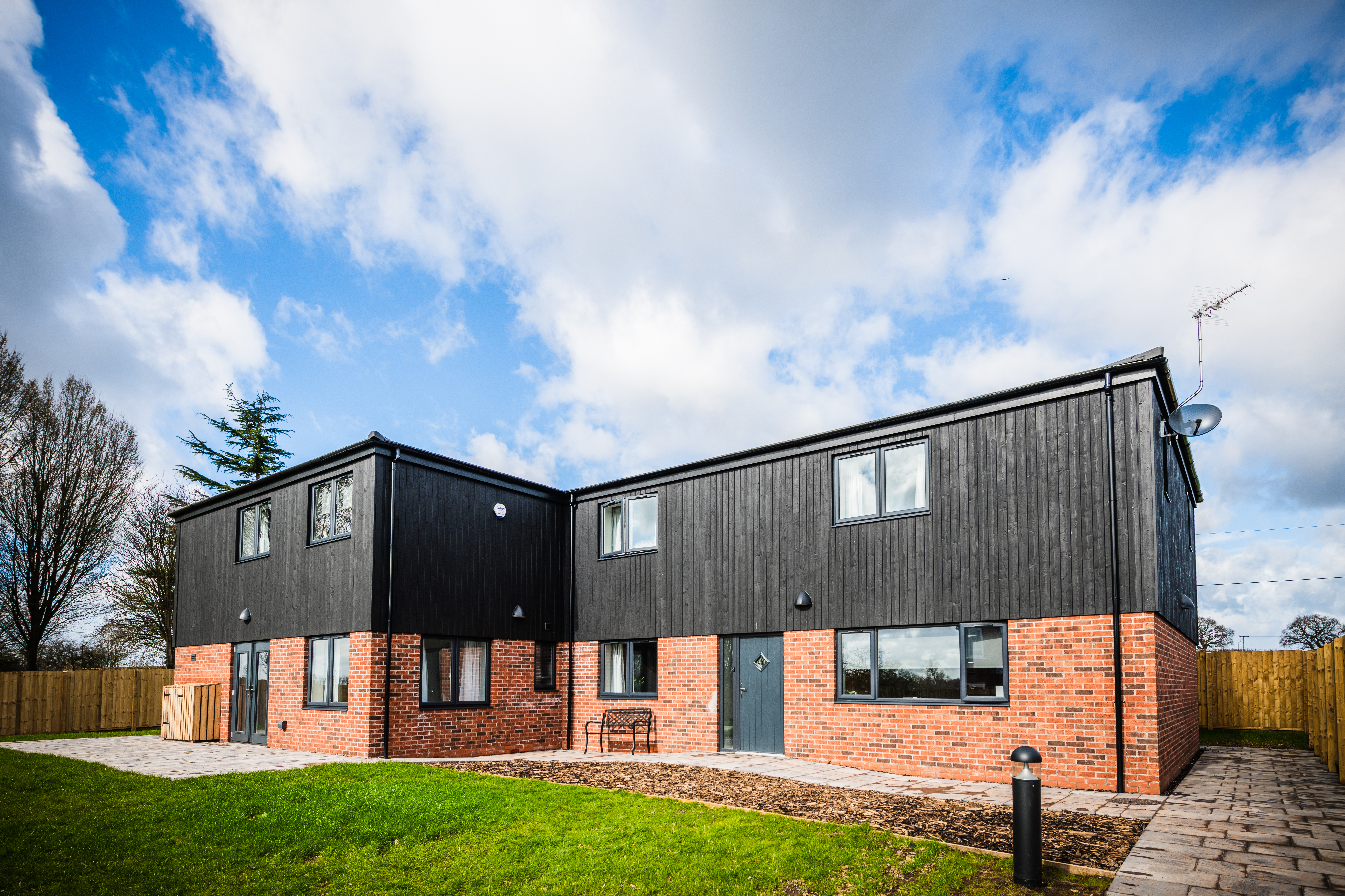 An outside photo from the front of Gableford with red brick and black panelling on a sunny day