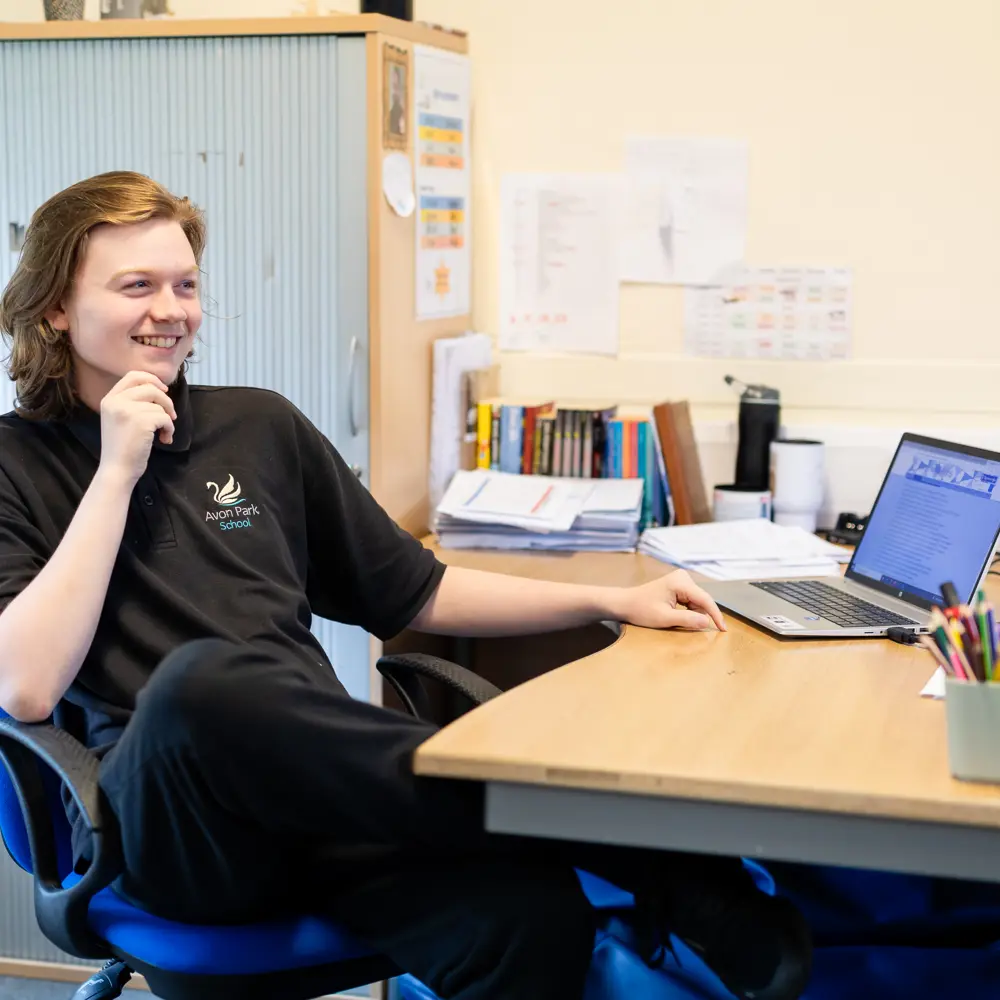 Smiling boy sat at a desk with laptop at Avon Park School
