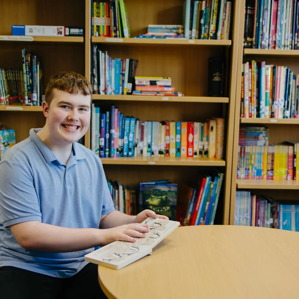 A young boy at Pontville School reading a book in the library