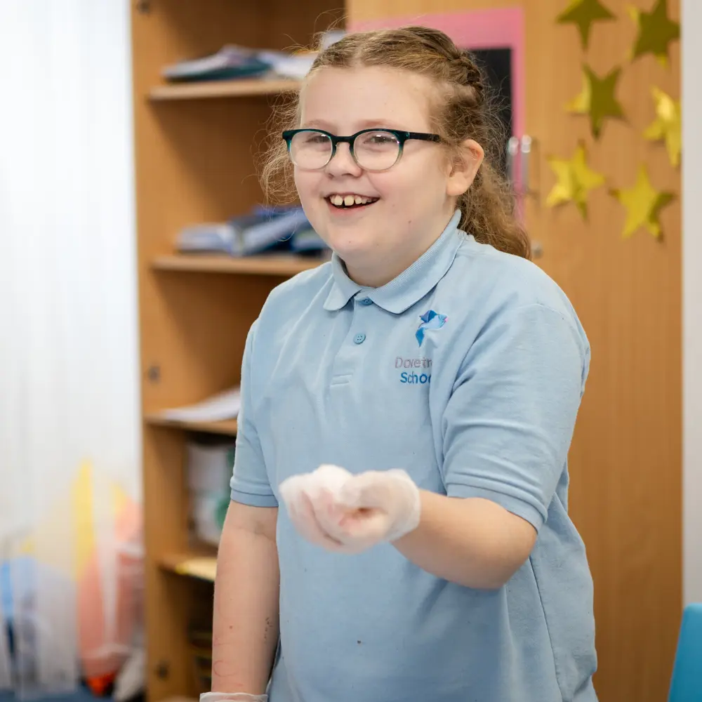 A young girl at Dovetree School laughing holding something in her hand