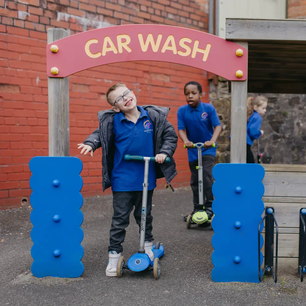 Two young boys at Westmorland School playing outside on scooters