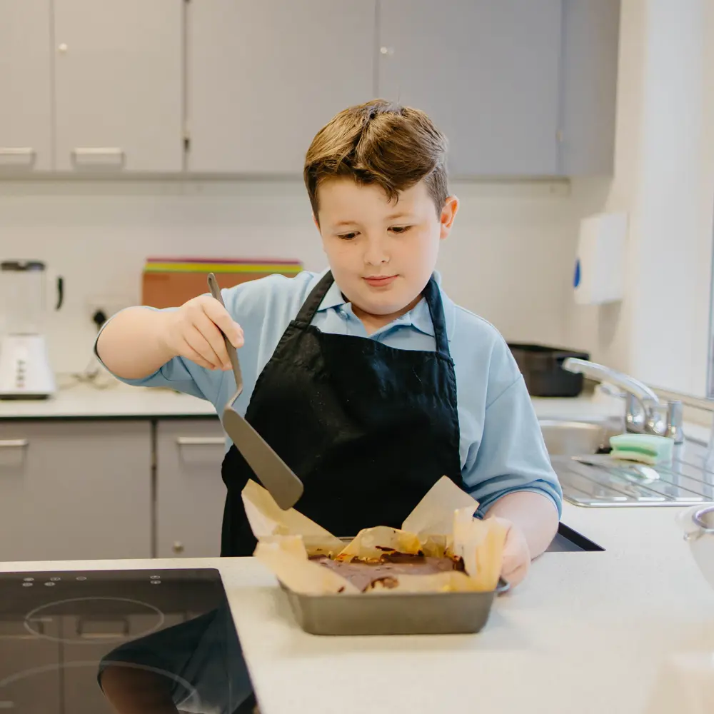 A young boy at Bescot Hall School baking a cake in food technology