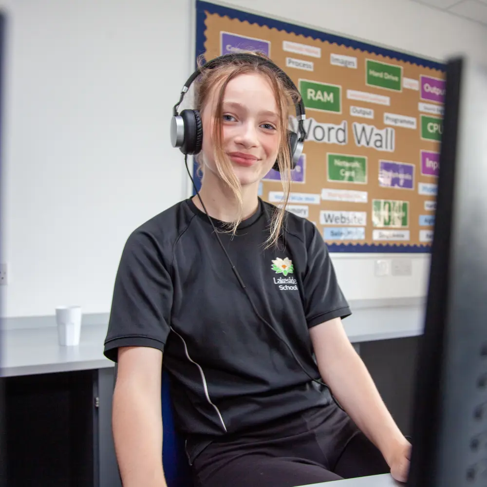 A young girl from Lakeside School wearing IT headphones sitting at a computer