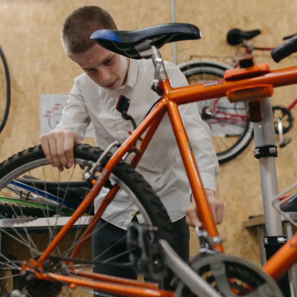 Boy inspecting an orange bicycle at Abbeywood School