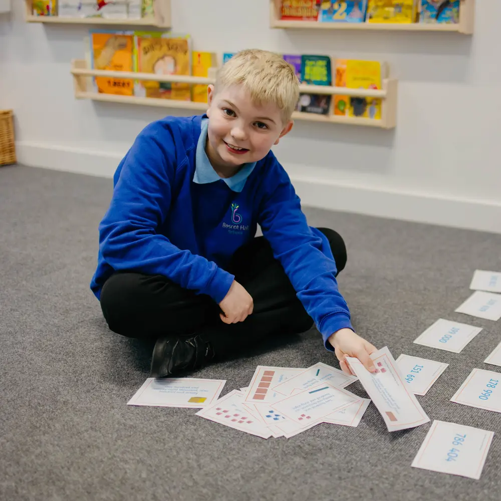 A young boy at Bescot Hall School sitting on the floor with visual cards