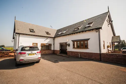 Outdoor photograph of The Grange on a sunny day with a car parked outside