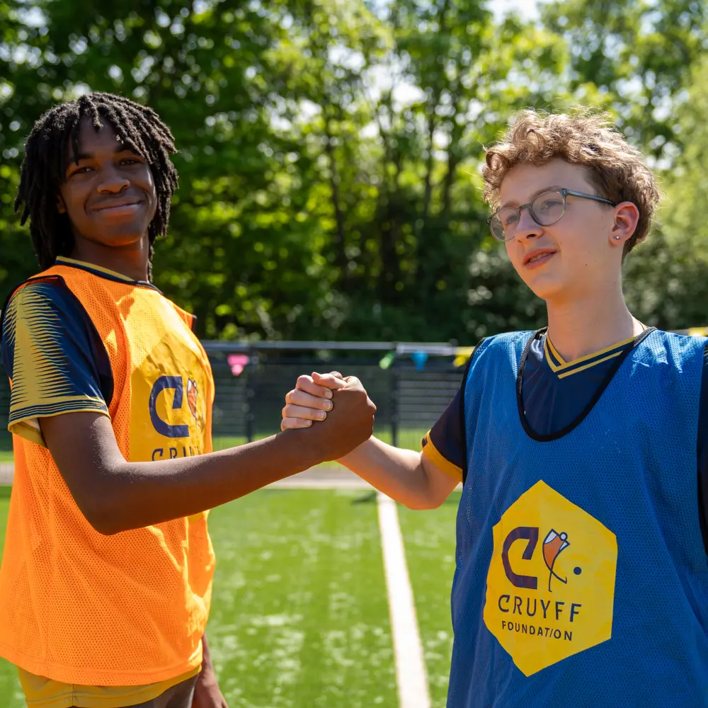 Two pupils from Chilworth House Upper School on the cruyff court shaking hands