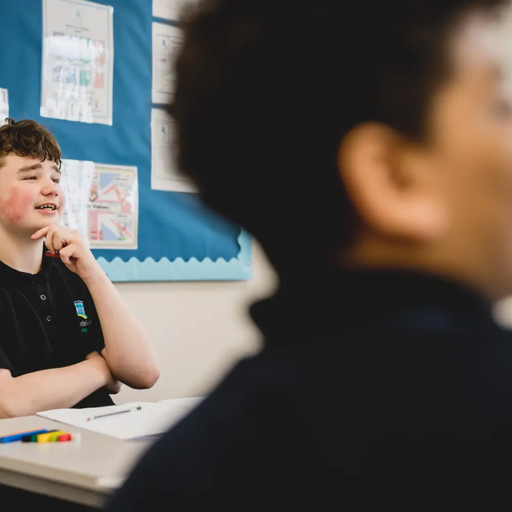 A young boy at Castlefell School sitting at a desk in a classroom engaging in the lesson