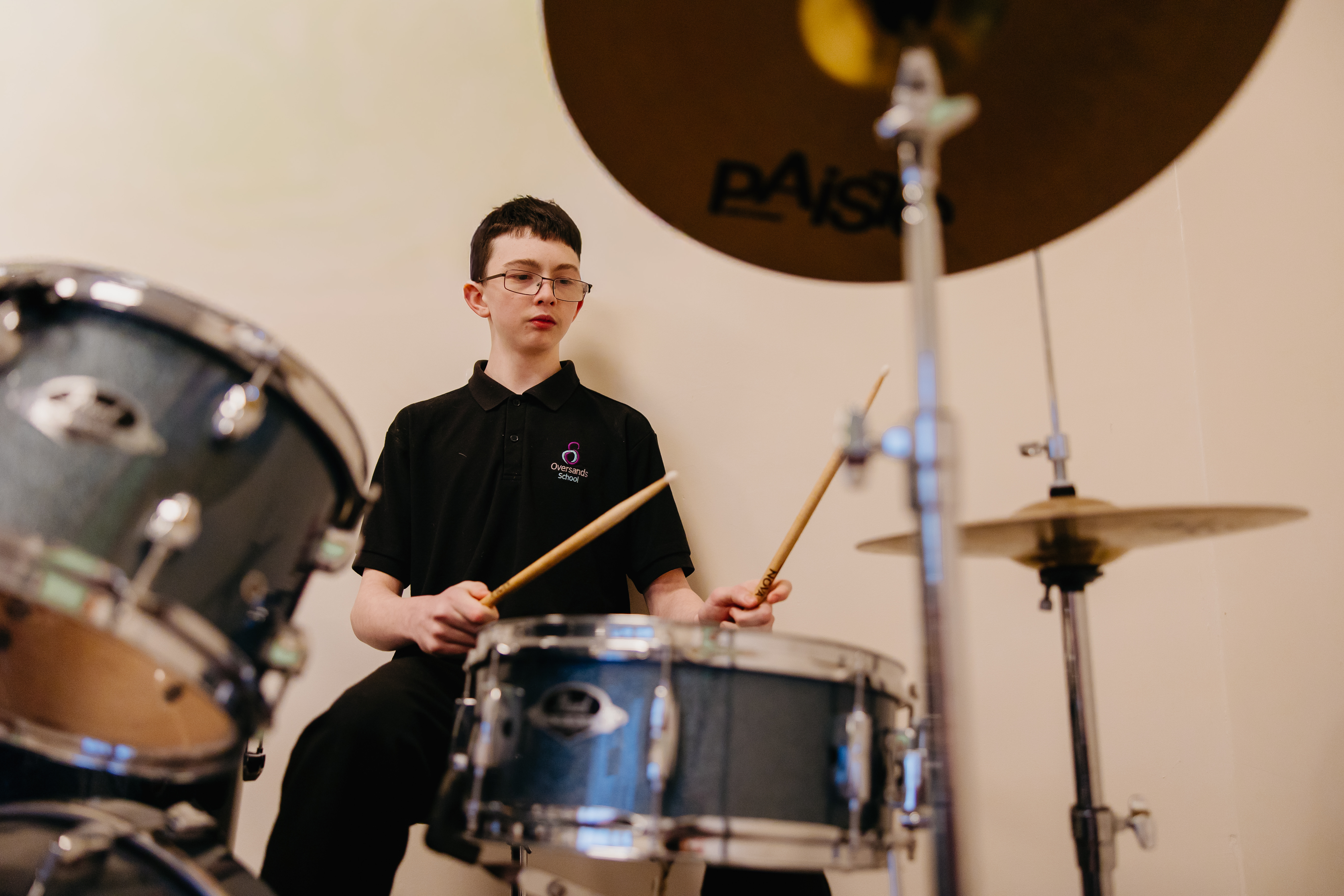 Boy sat at drum set holding drum sticks