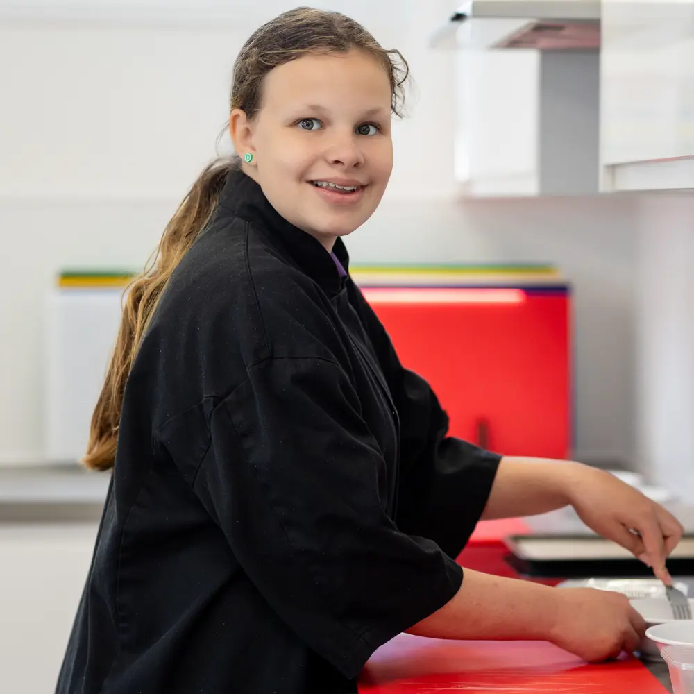 Young girl with light brown hair cooking at Bramley Hill School