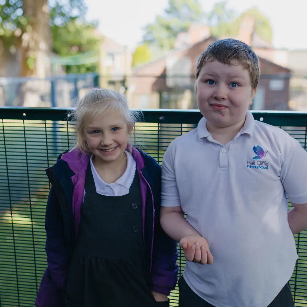Two young pupils at Hall Cliffe Primary School outside smiling for a photo