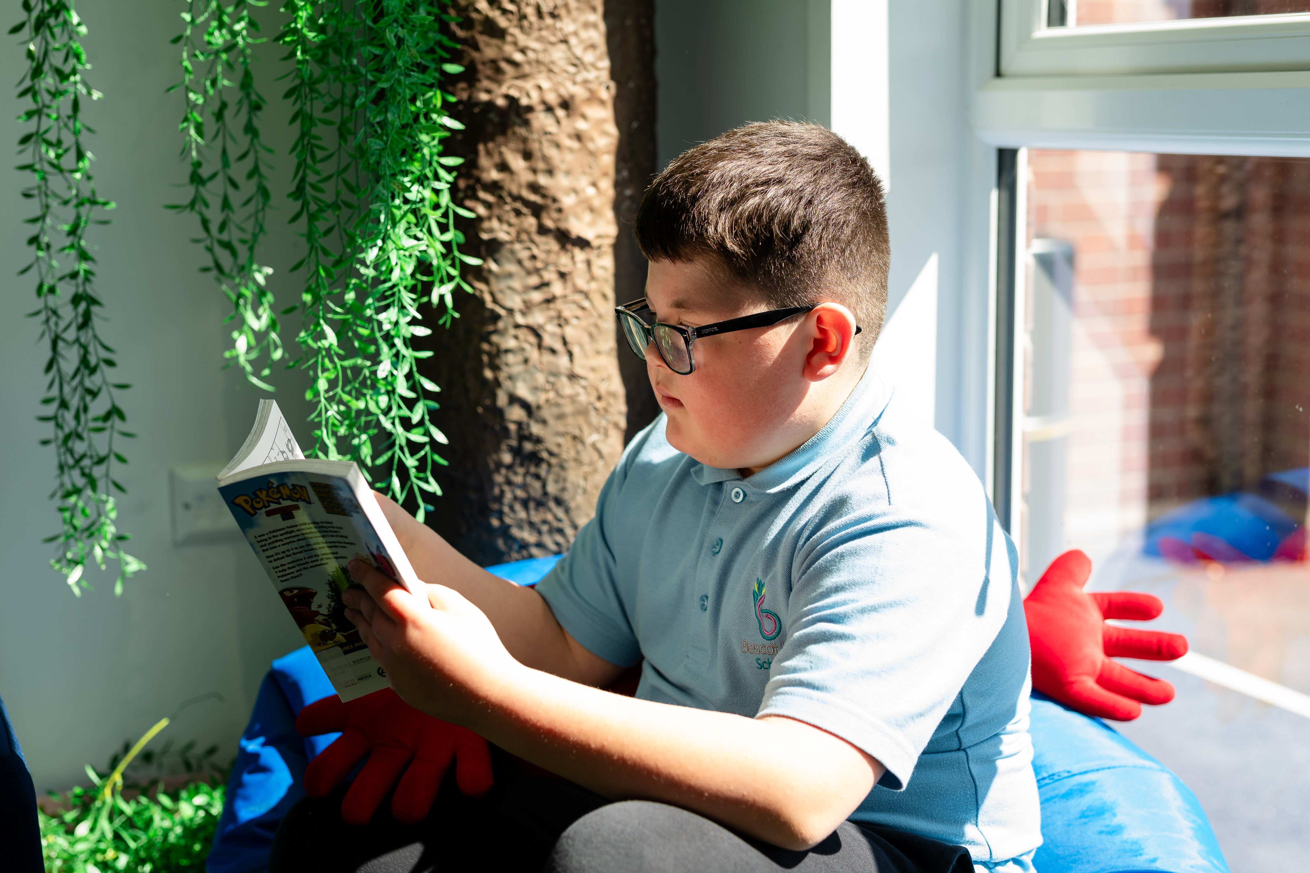 Boy sat on beanbag in classroom reading his book