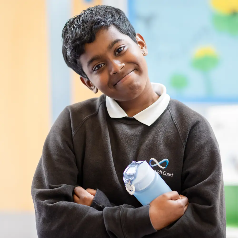 Young boy from Luxborough Court School holding a water bottle smiling at camera