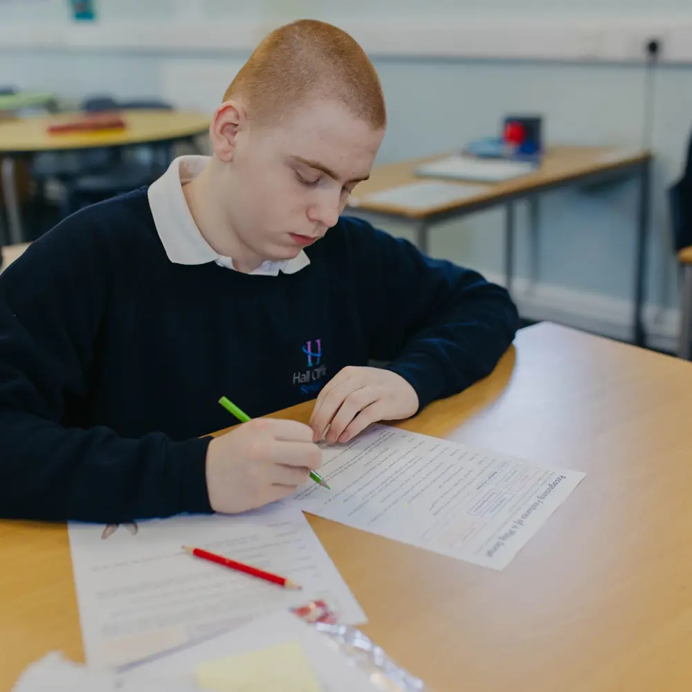 A student from Hall Cliffe School in a navy blue uniform doing a worksheet in a classroom