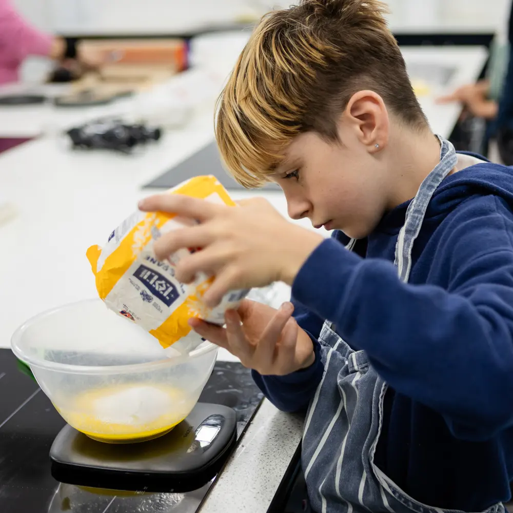 A young boy at Queensmead House School measuring out ingredients in a food technology class