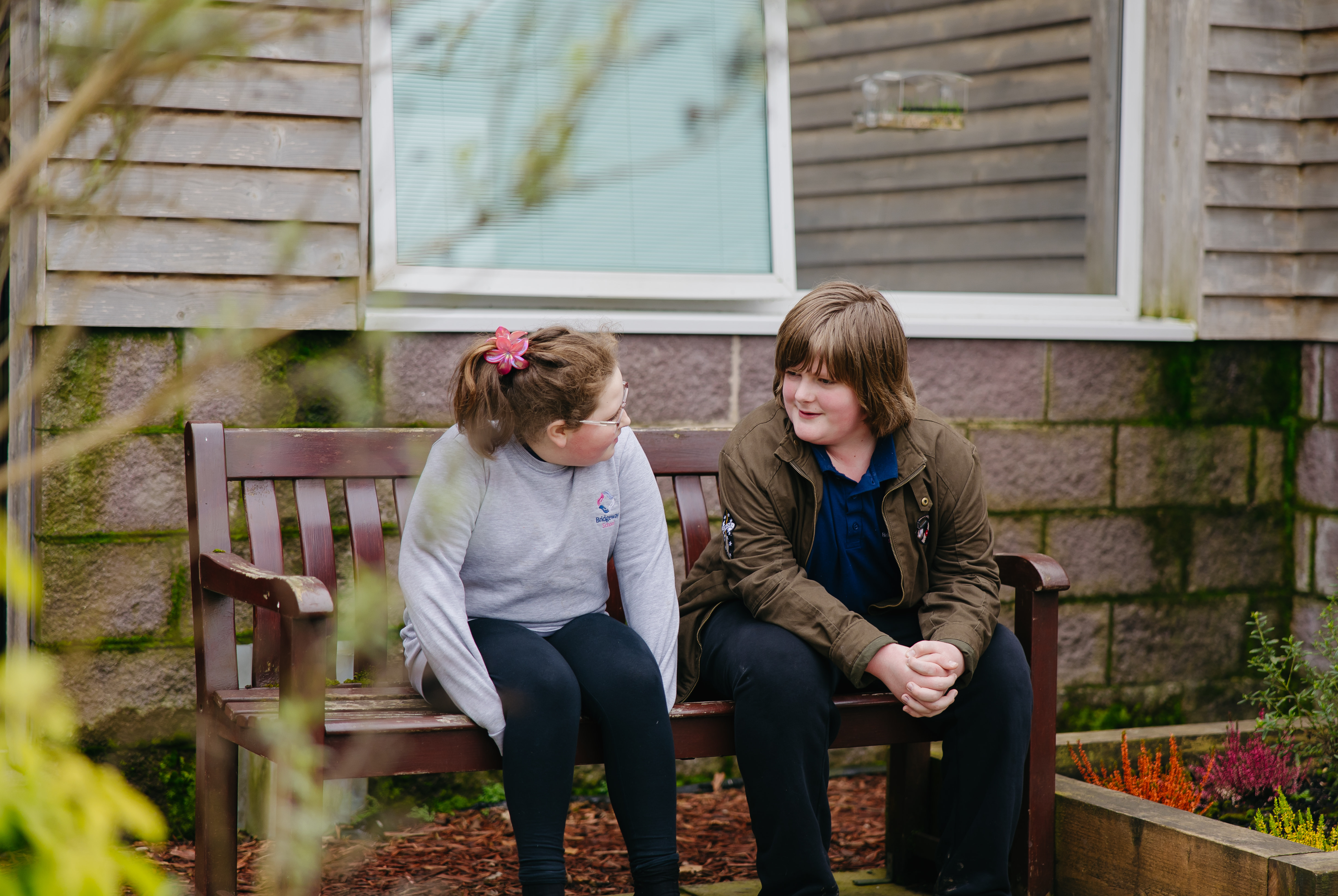 Two puupils having a conversation on a bench outside