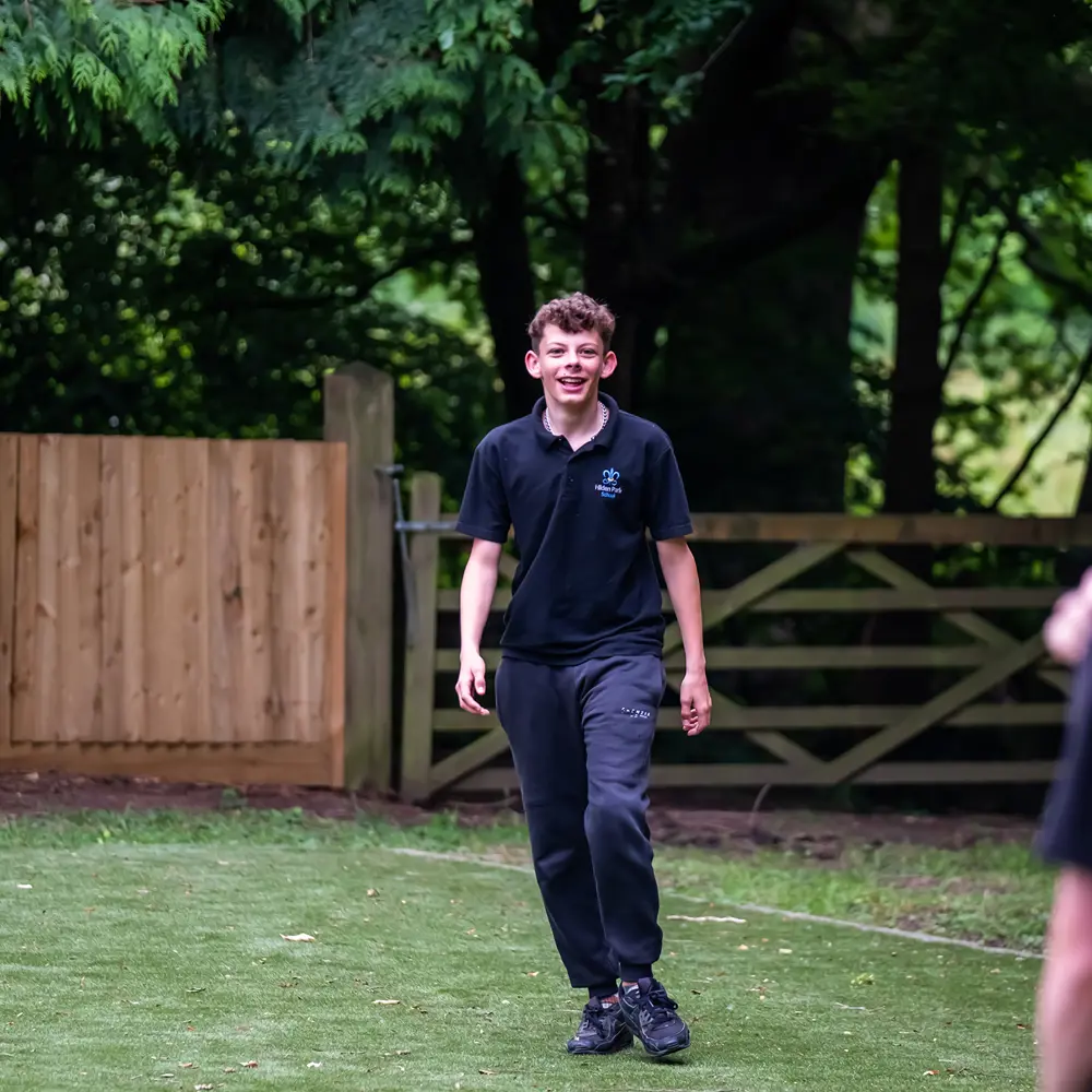 Pupil with brown hair at Hilden Park School smiling at another pupil outside