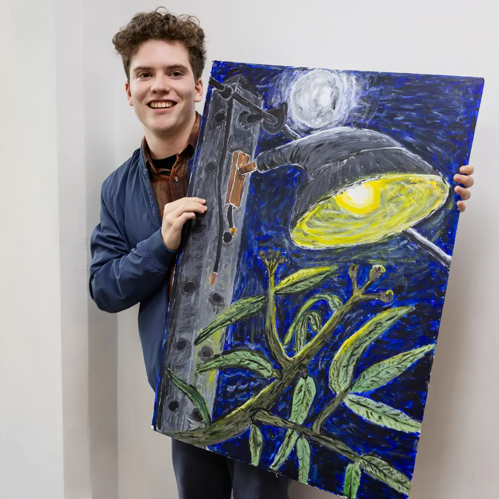 A young boy from Greenholm School holding up his painting