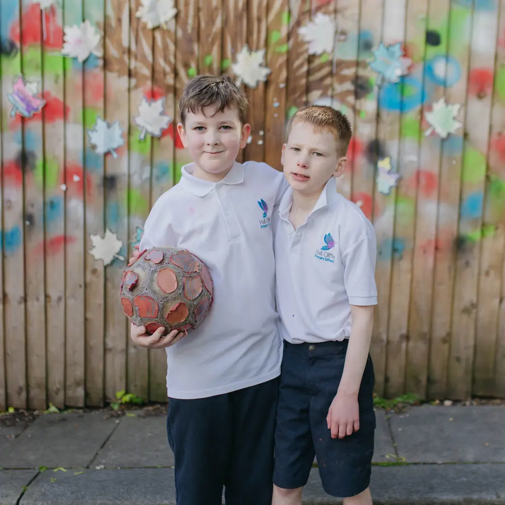 Two boys from Hall Cliffe Primary School outside with their arms around each others shoulders