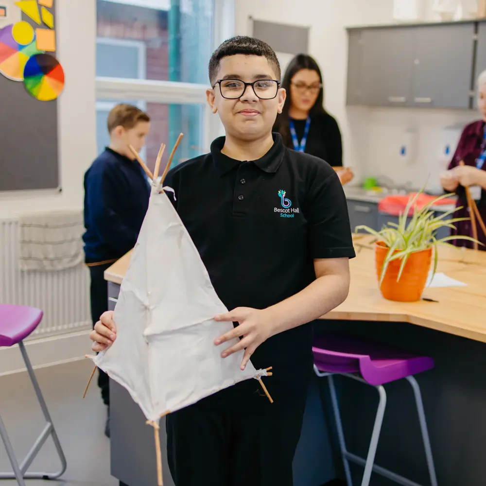 A young boy at Bescot Hall School holding a homemade model tent