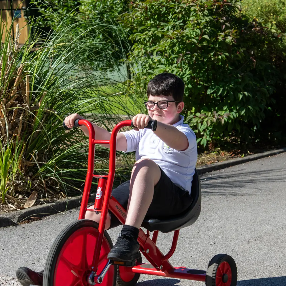 A young boy at Lakeside School on a bike outside