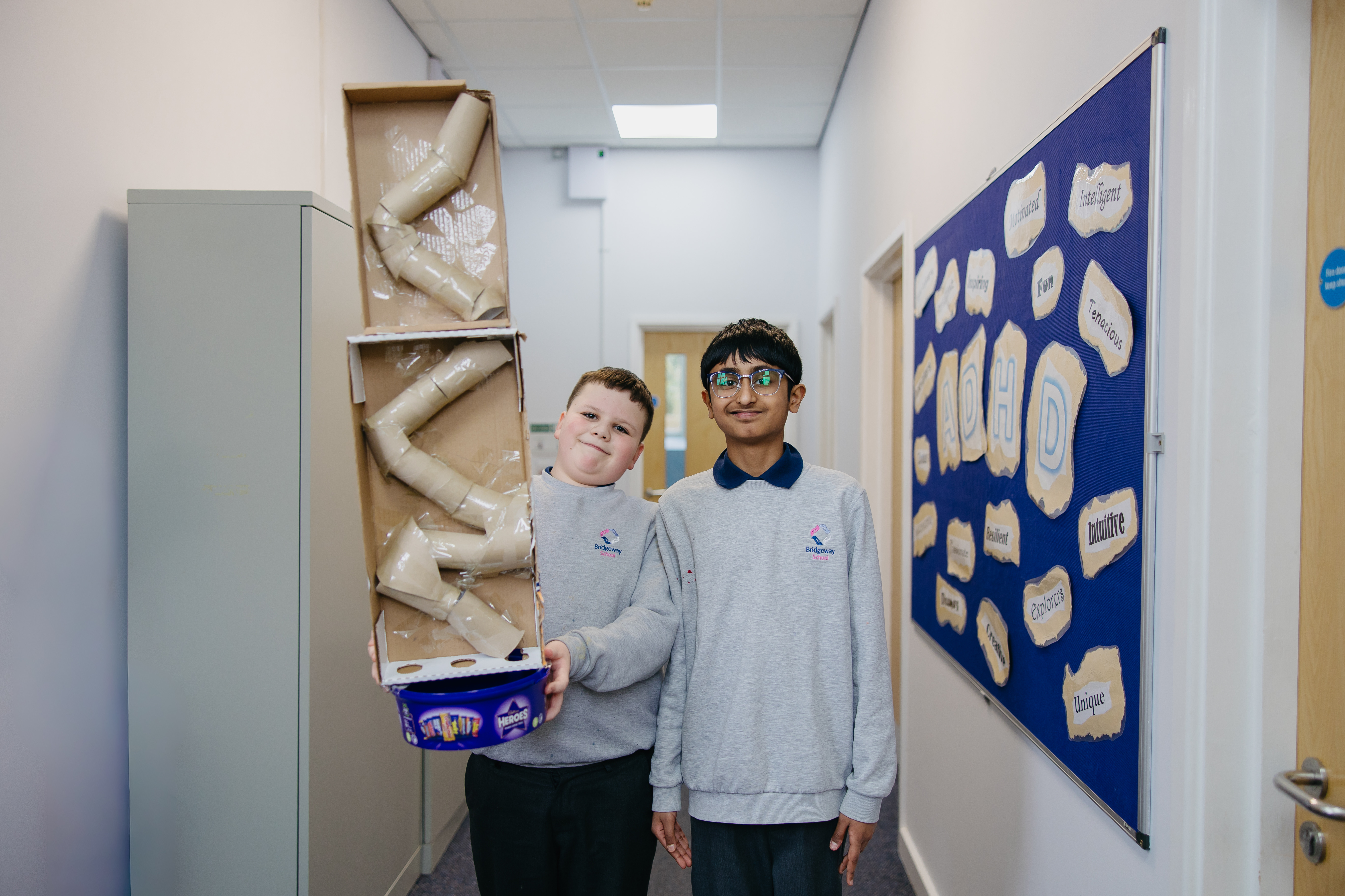Two boys sttod side-by-side with cardboard project
