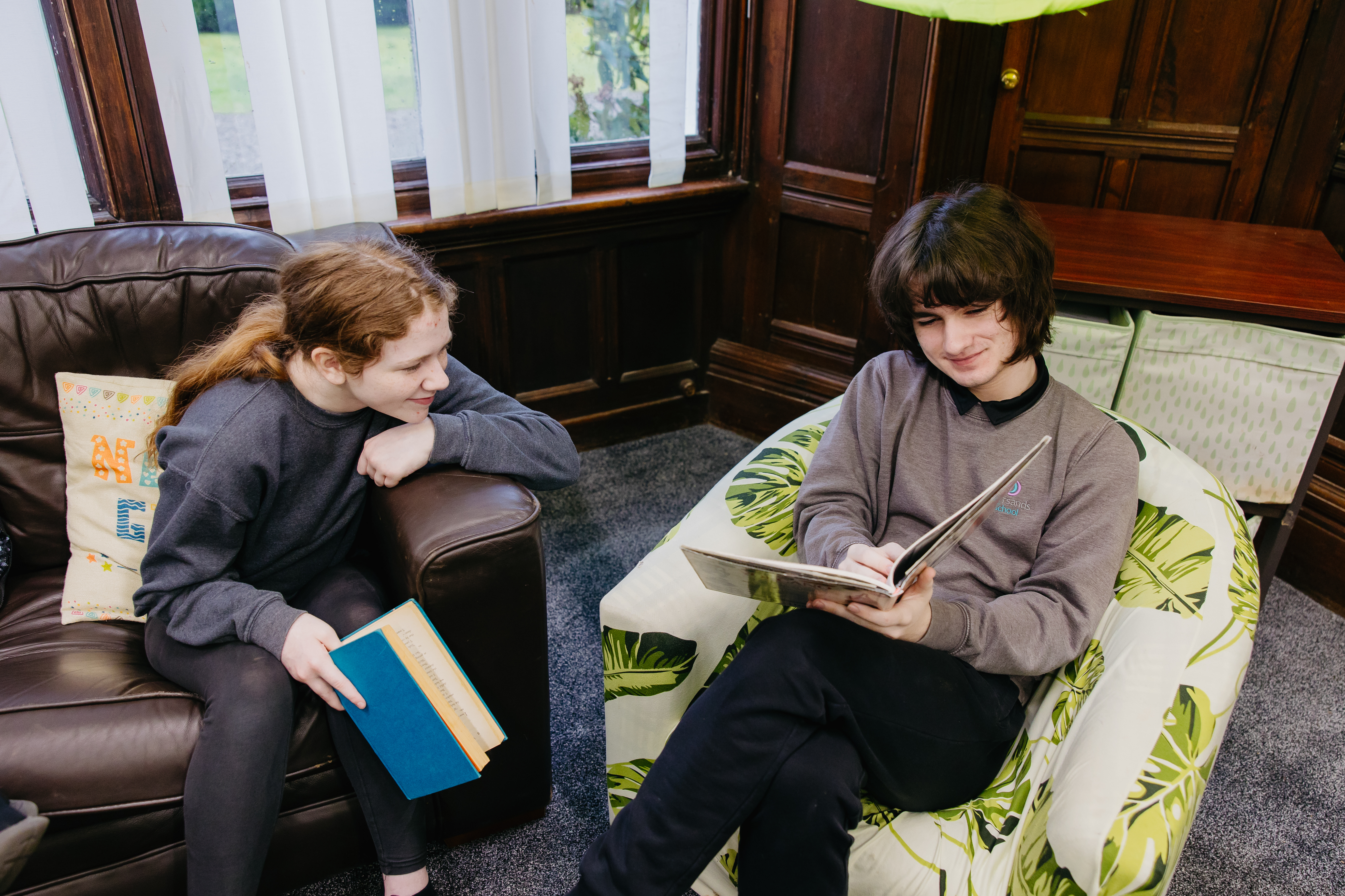 Two pupils sat in a library reading books